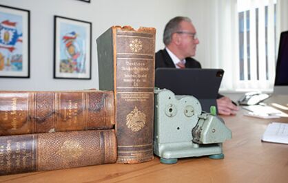 Das Reichs-Gesetzbuch und eine alte Rechenmaschine auf einem Bürotisch